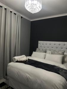 a bedroom with a large white bed with a chandelier at P Daisy in Rundu