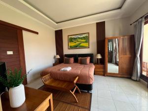 a bedroom with a bed and a chair and a table at Surya Guest House Sanur in Sanur