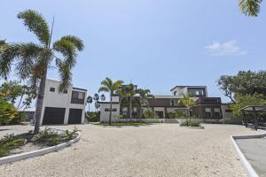 a house with palm trees and a gravel driveway at Beyond the Blue Casita in Placencia