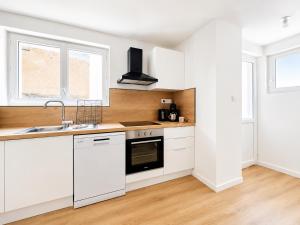 a kitchen with white cabinets and a sink at 8B - Le Cosy in Saint-Rambert-dʼAlbon