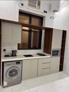 a kitchen with a washing machine and a microwave at شقق ميلا الباحة الفاخرة in Al Baha