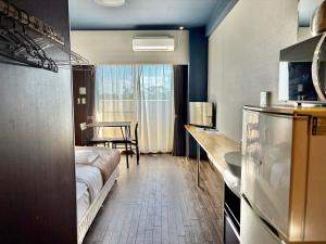 a room with a bed and a table and a kitchen at HOTEL Progress inn 名護 MATABee in Nago