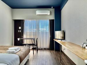 a hotel room with a bed and a desk and a table at HOTEL Progress inn 名護 MATABee in Nago
