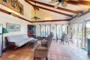 a living room with a bed and chairs and windows at Condo #23 @ Beachside Villas in Placencia