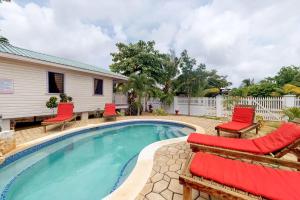 a swimming pool with red chairs and a house at Starfish Cabana at Latitude Adjustment -Gold Standard Certified in Hopkins