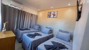 a room with three beds with blue pillows at Suítes Rufino in Lençóis