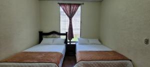 two beds in a room with a window at casa bugambilia in San Martín Zapotitlán