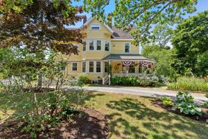 a yellow house with a yard at Inn at the Oaks in Eastham