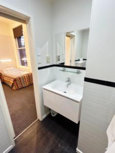 a white bathroom with a sink and a mirror at Leviathan Hotel in Dunedin +35 photos