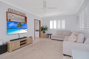 a living room with a couch and a flat screen tv at Zilzie Beach House in Zilzie