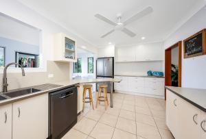 a kitchen with white cabinets and a ceiling fan at Zilzie Beach House in Zilzie