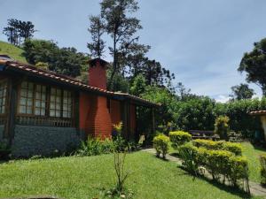 a house with a brick chimney and a yard at Chalé Mauá Conforto e Arte in Visconde De Maua