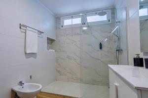 a white bathroom with a shower and a sink at Achadinha Sunset House - São Miguel, Açores in Achadinha +31 photos