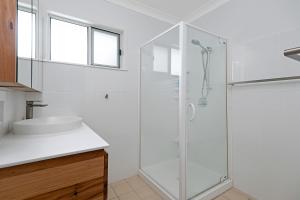 a bathroom with a glass shower and a sink at Zilzie Beach House in Zilzie +22 photos