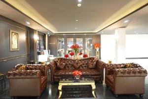a living room with a brown leather couch at Taris Art Hotel Phrae in Phrae