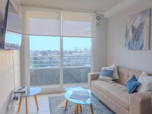 a living room with a couch and a large window at Apart Total Aldunate Temuco Centro 2 in Temuco