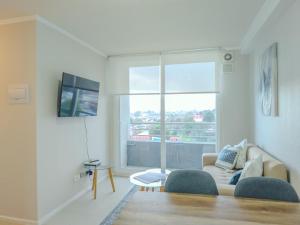 a living room with a couch and a large window at Apart Total Aldunate Temuco Centro 2 in Temuco +12 photos