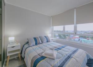 a white bedroom with a bed with a window at Apart Total Aldunate Temuco Centro 2 in Temuco