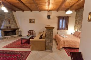 a bedroom with a bed and a couch and a fireplace at Althaia in Ano Chora
