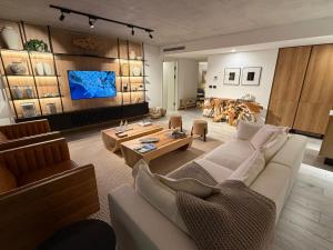 a living room with a white couch and a tv at Surfside - 3 Suítes - 4 Bathroom in Punta del Este