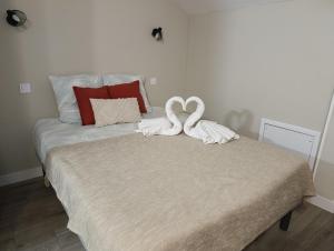 a bed with two swans towels on top of it at Studio Havane avec clim in Bourbonne-les-Bains