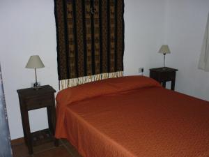 1 dormitorio con 1 cama naranja y 2 mesitas de noche en Cabañas Los Quijotes en San Marcos Sierras