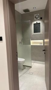 a bathroom with a toilet and a television on the wall at Rose House 2 in Taif
