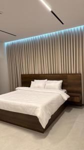 a bedroom with a large bed with white sheets at Rose House 2 in Taif