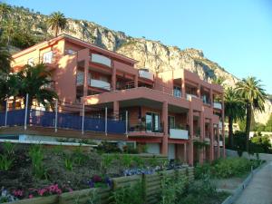 a building with palm trees and a mountain in the background at Appartement au Chateau Vallaya in Menton