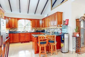 a large kitchen with wooden cabinets and bar stools at The Pine Tree Villa in San Ignacio