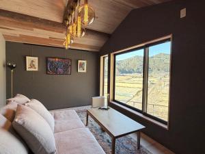 a living room with a couch and a large window at KUMANOYASAI Cottage in Chikatsuyu in Tanabe