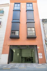an orange building with blue windows on a street at Apartamento Eursu centro con piscina in Málaga
