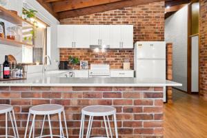 a kitchen with a brick wall and a white refrigerator at Hunter Valley 2 x Homes Pets Heated Pool in Whittingham