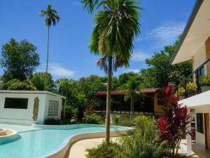 a swimming pool with a palm tree next to a building at Para Hill Homestay in Ban Muang Mai