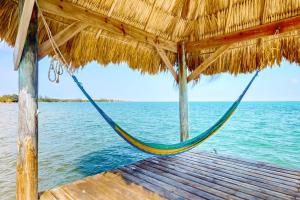 a hammock hanging from a straw hut over the water at Ocean Edge Gold Standard Certified in Maya Beach