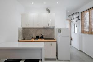 a kitchen with white cabinets and a white refrigerator at Ambra Luxury Suite 18 in Kallithea Halkidikis