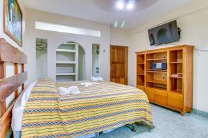 a bedroom with a large bed with a tv on it at Suite Junior at Midas Belize in San Ignacio