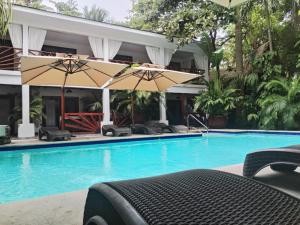 a swimming pool with chairs and umbrellas next to a building at Locanda Samara Beach in Sámara
