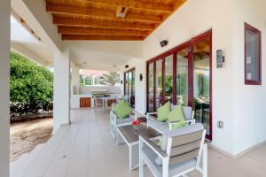 a porch with white chairs and a wooden ceiling at Green Tower House in Placencia