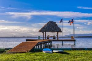 a wooden pier with a grass roofed gazebo on the water at Poseidon House in Riversdale