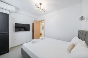 a white bedroom with two beds and a tv at Ambra Luxury Suite 18 in Kallithea Halkidikis