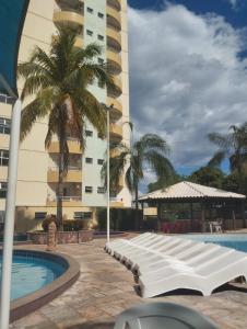 a hotel with a pool and palm trees and a building at Thermas place 406 in Caldas Novas