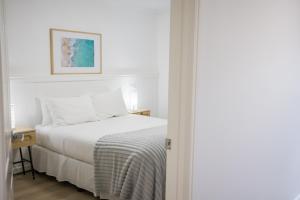 a white bedroom with a bed and a picture on the wall at Albany Central Apartments in Albany