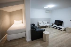 a bedroom with a bed and a chair and a television at Albany Central Apartments in Albany
