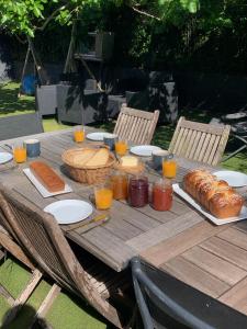 a wooden table with bread and glasses of orange juice at Suite-piscine et jacuzzi sous les étoiles - petit déjeuner inclus ou non, et repas froid en option in Septème