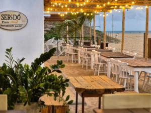 a restaurant on the beach with tables and chairs at NaPraia Brasil Pousada in São Miguel do Gostoso