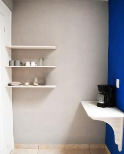 a kitchen with white shelves and a blue wall at Sensity Home Habitación 5 A Cómoda y calida con baño compartido in Tehuacán
