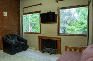a living room with a fireplace and a chair and a television at Potrerillos Nuestras Raíces in Potrerillos