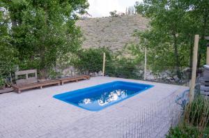 a blue swimming pool next to a bench and a bench at Potrerillos Nuestras Raíces in Potrerillos