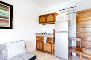 a small kitchen with a refrigerator and a sink at Charming Suite with WiFi AC Shared Pool Grill Area & Rooftop Deck in Caye Caulker